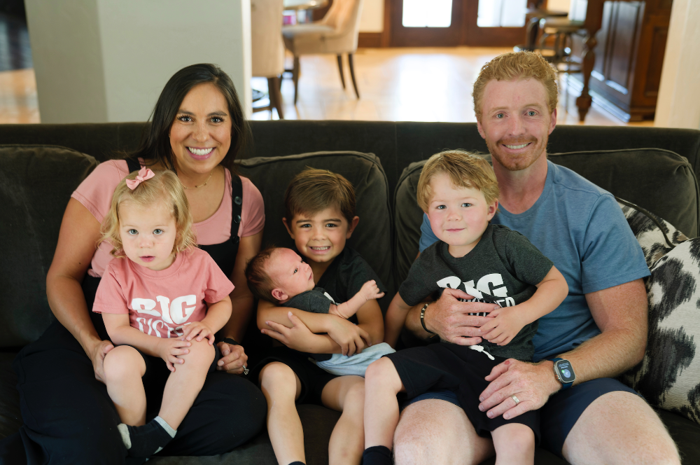 Family of six sitting on a couch in a living room.